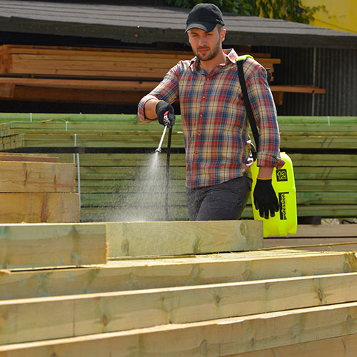 Ein Mann färbt Holz mit dem P12P Farbsprüher ein, idealer Drucksprüher zum Auftragen von Holzschutzmitteln, Beizen und Farben auf Holzoberflächen im Außenbereich